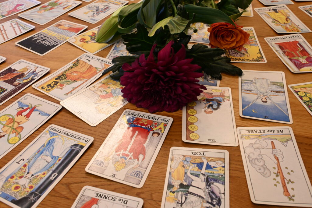 Weit ausgelegte Tarotkarten mit dunkelroter Dahlie in der Bildmitte