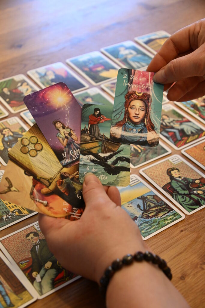 Zwei Hände halten farbenfrohe, moderne Tarotkarten über einem Kartenspiel