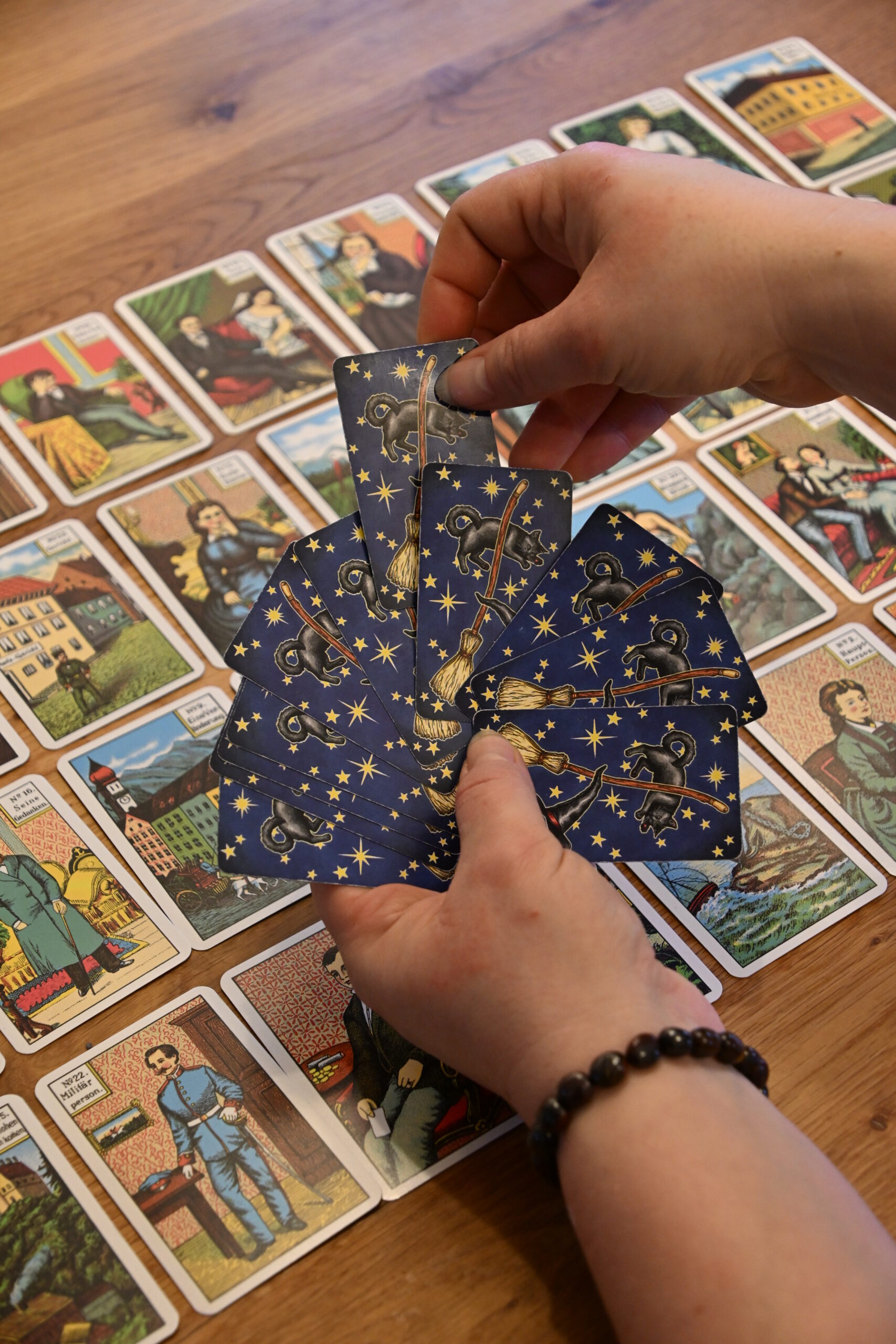 Hand hält eine Tarotkarte mit Sternenmotiv über ausgelegten Karten